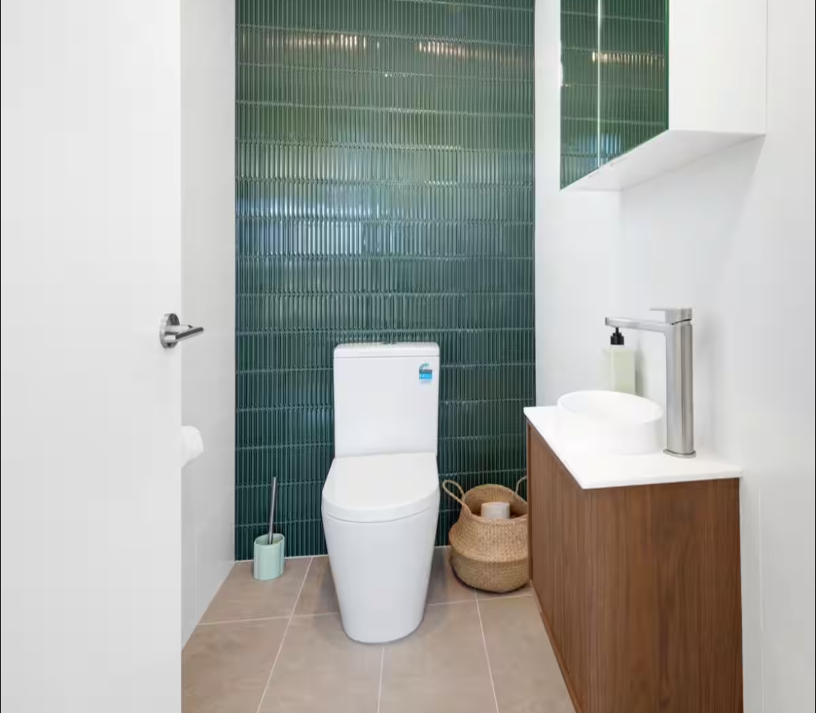 A spotless powder room with green tiles